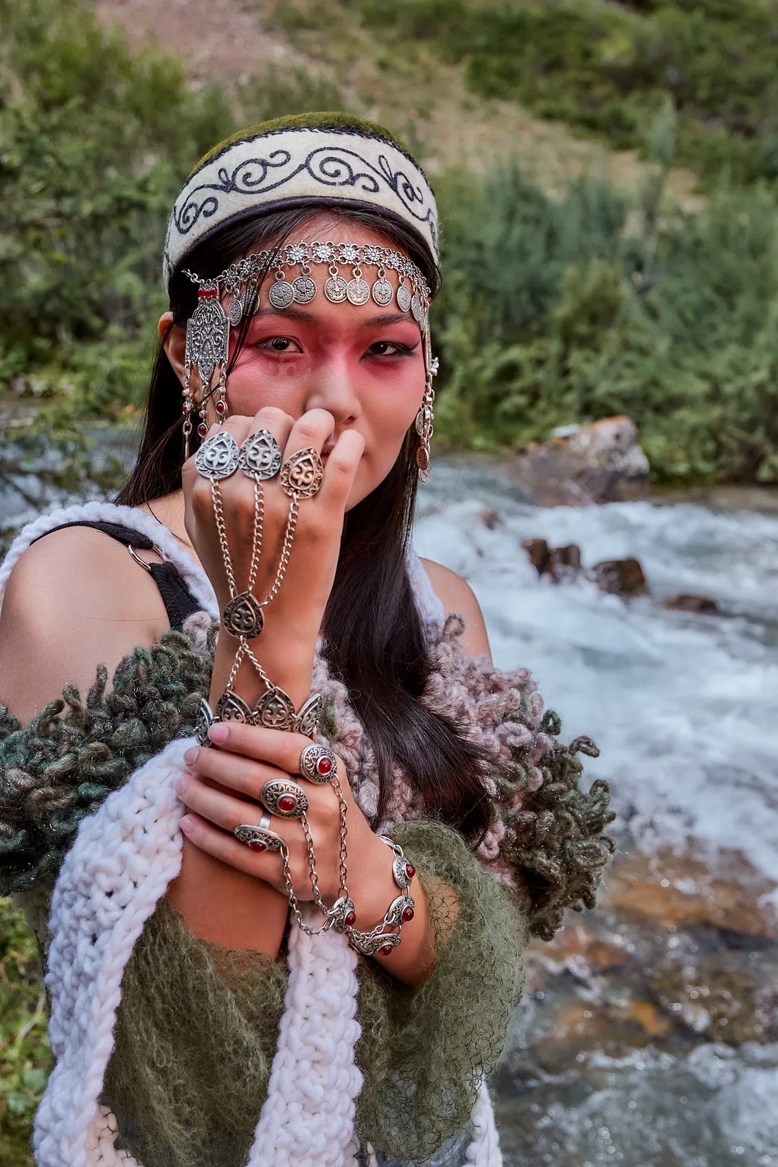 Hands with silver jewellery raised to the face